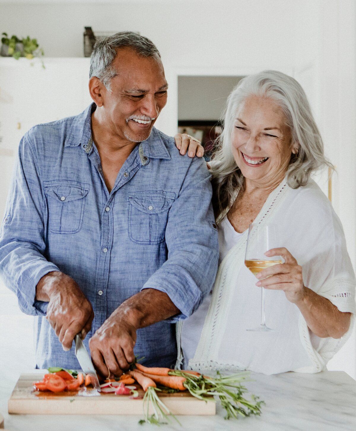 Happy sermorelin patient model couple cooking together in a bright kitchen.