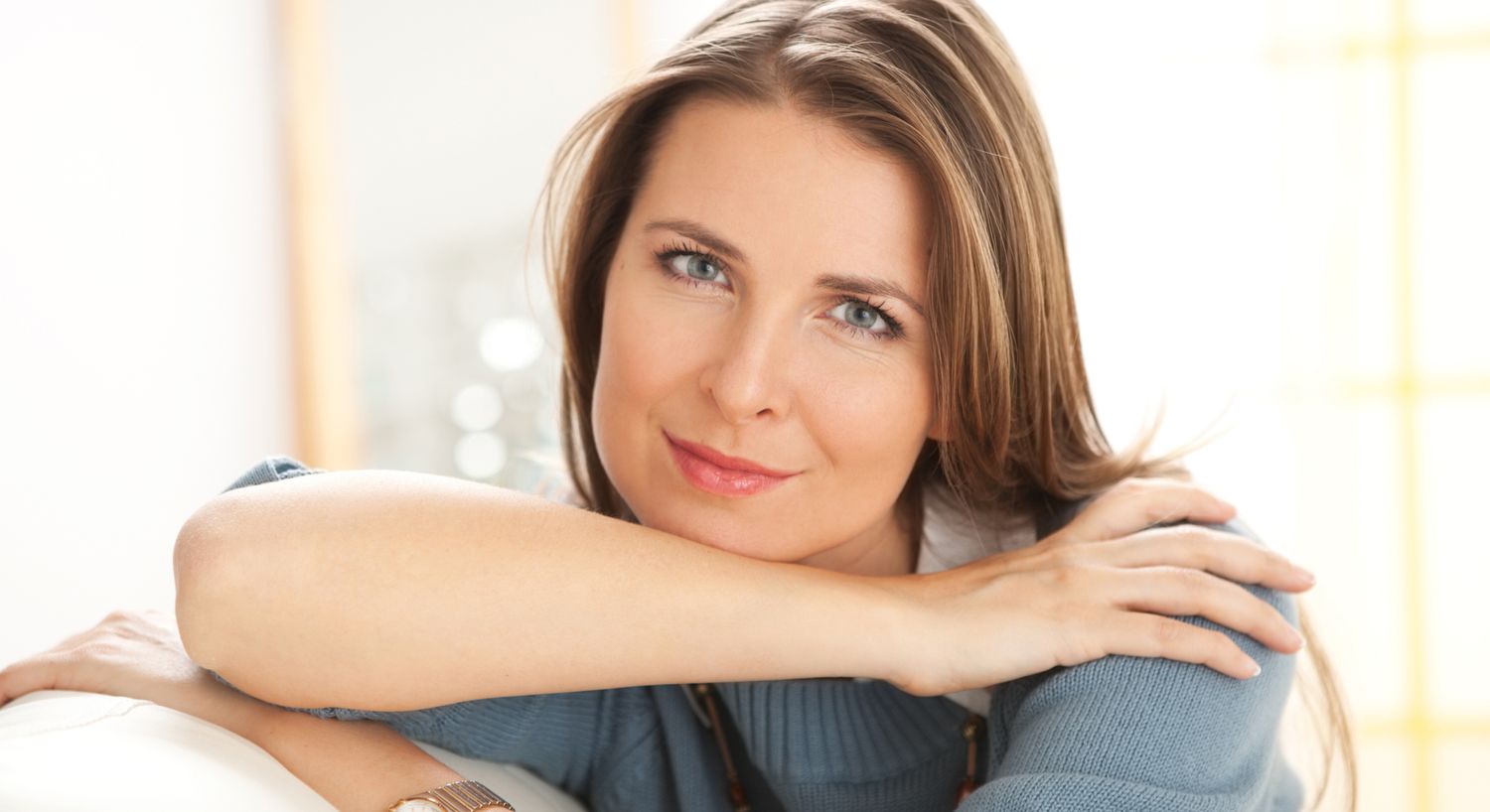 Inner Beauty IV therapy patient model with brown hair sitting on a couch resting her chin on her arm