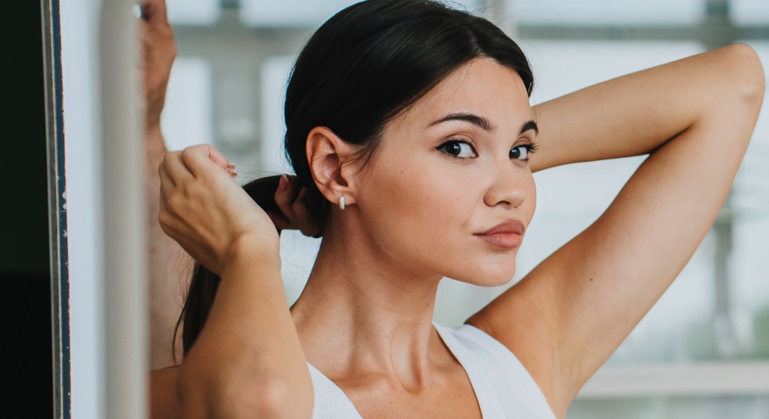 Ultherapy patient model fixing her hair in the mirror